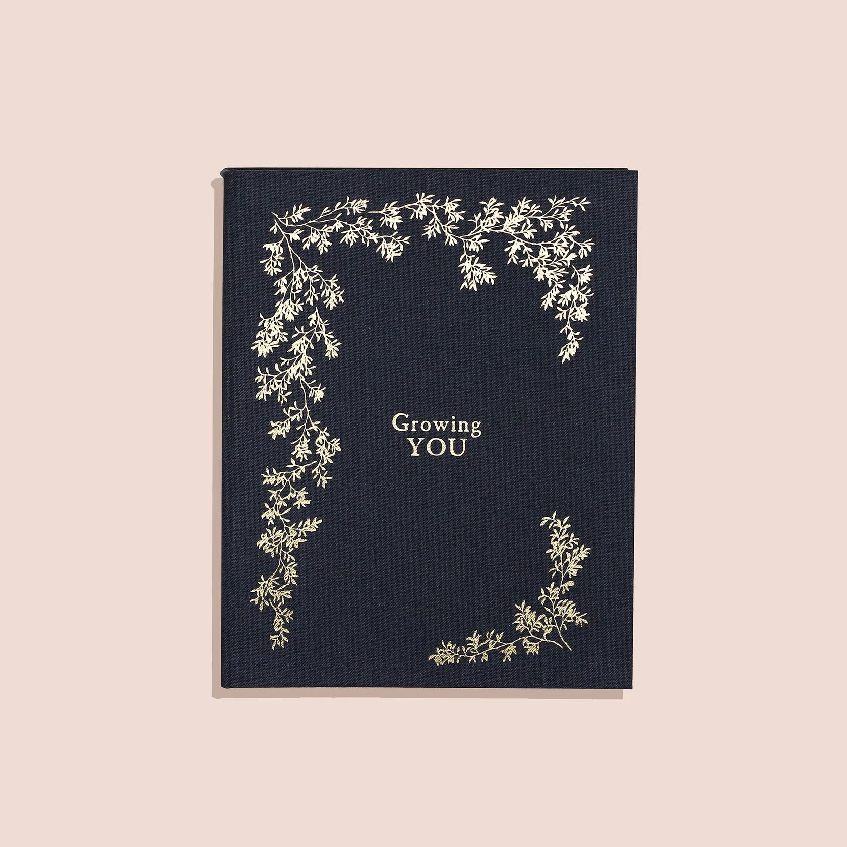A navy-colored pregnancy memory book titled 'Growing You' with floral designs and the author's name Korie Herold on the cover.