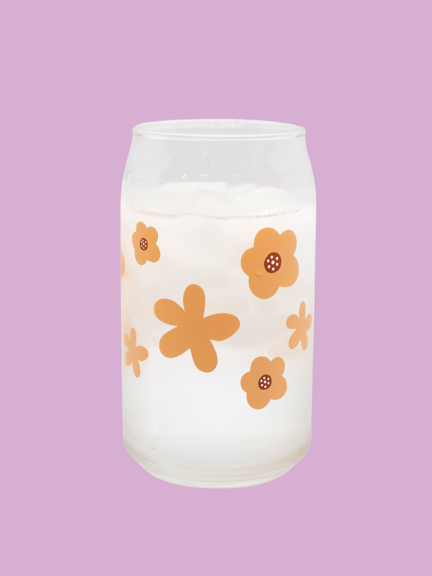 A clear can-shaped glass with a design of peach colored flowers wrapped around.