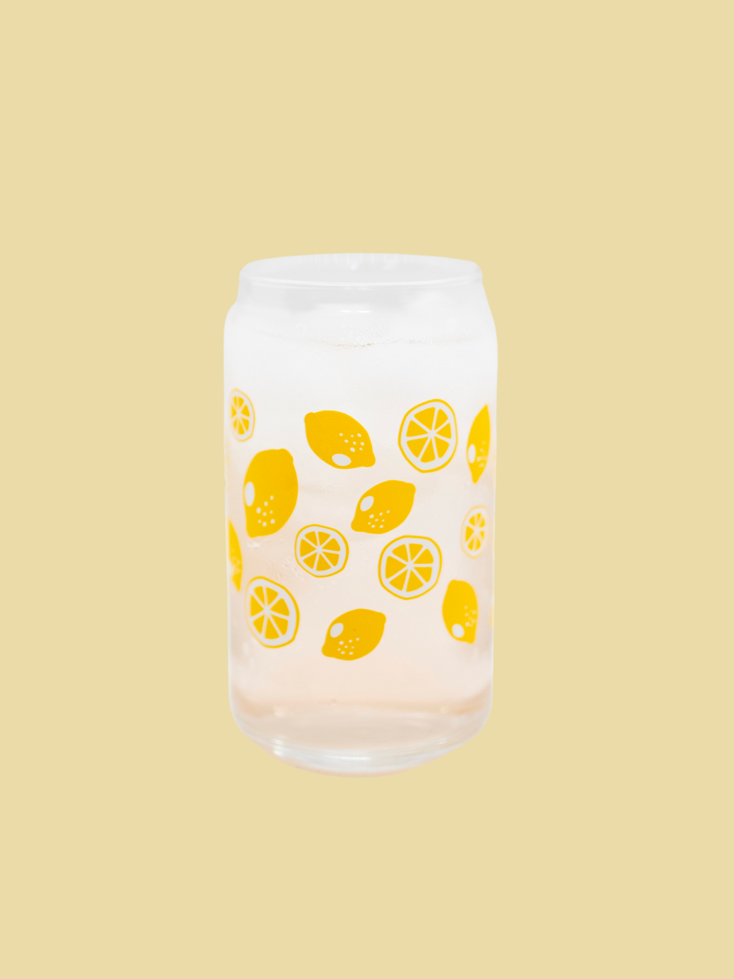 A clear can-shaped glass with lemon design wrapped around.