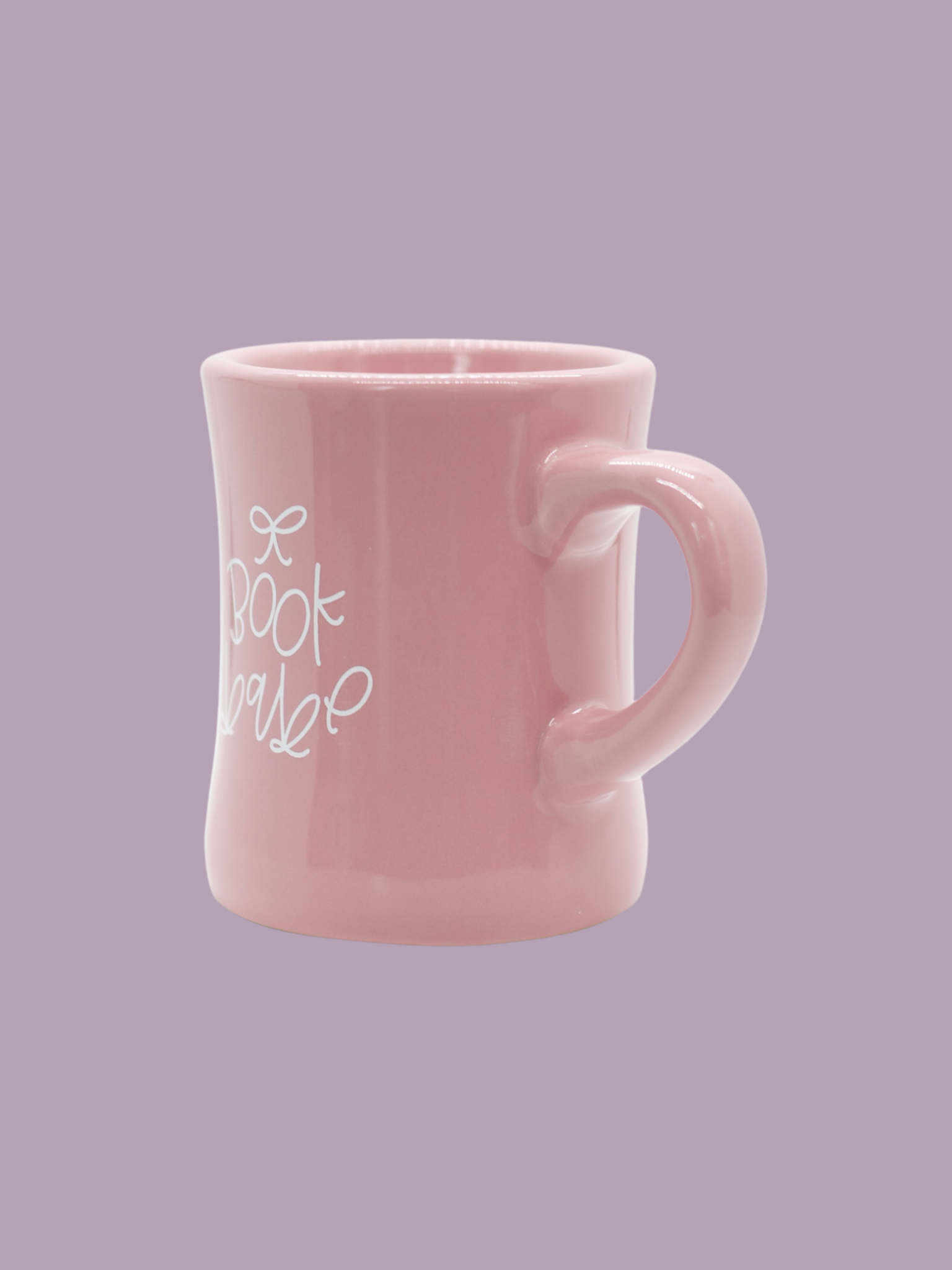 A glossy pink ceramic mug with 'book babe' printed in white hand-lettering and a small bow detail.