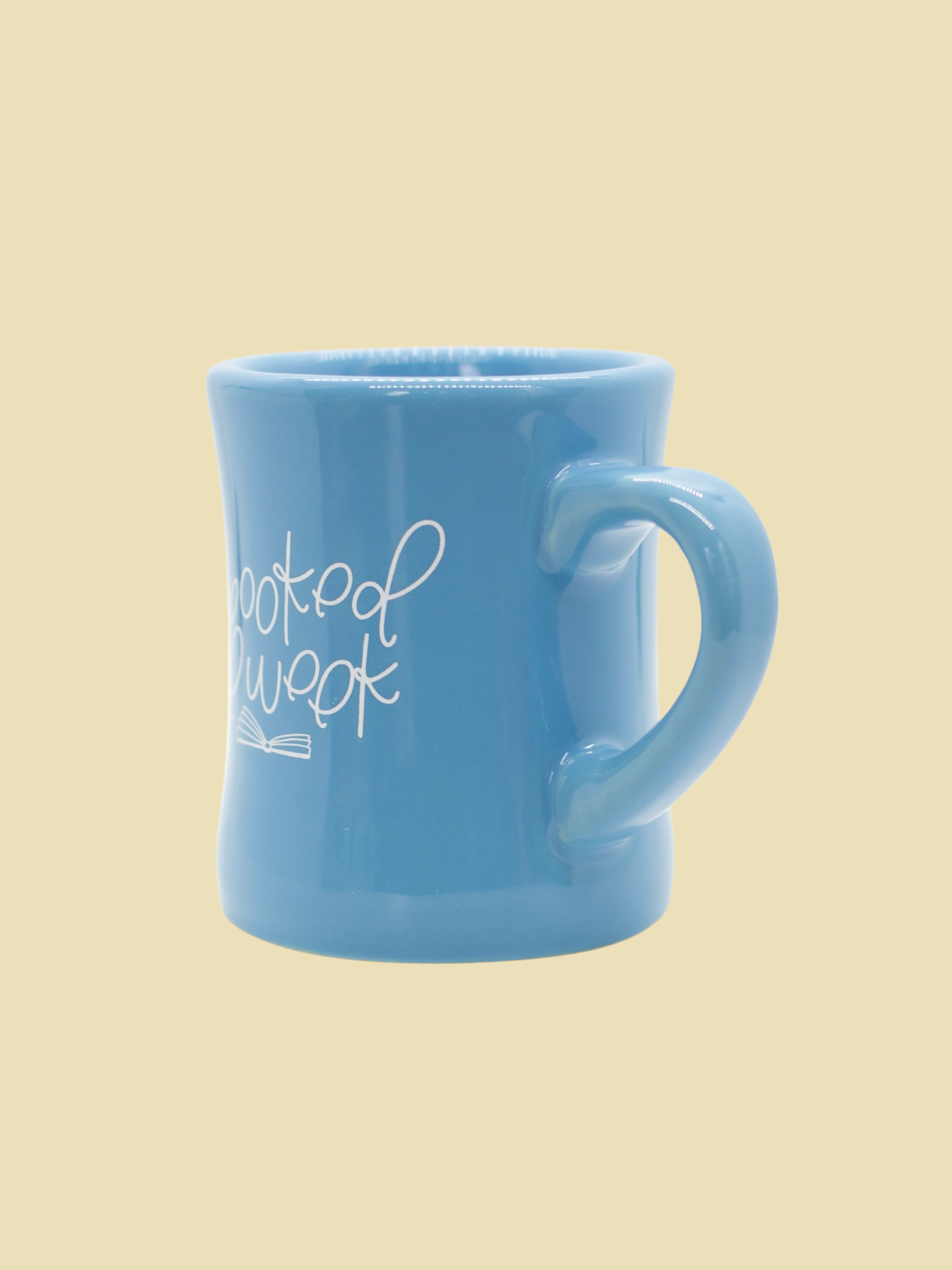 A blue ceramic mug with the text 'I'm booked all week' printed on it, featuring an open book graphic.