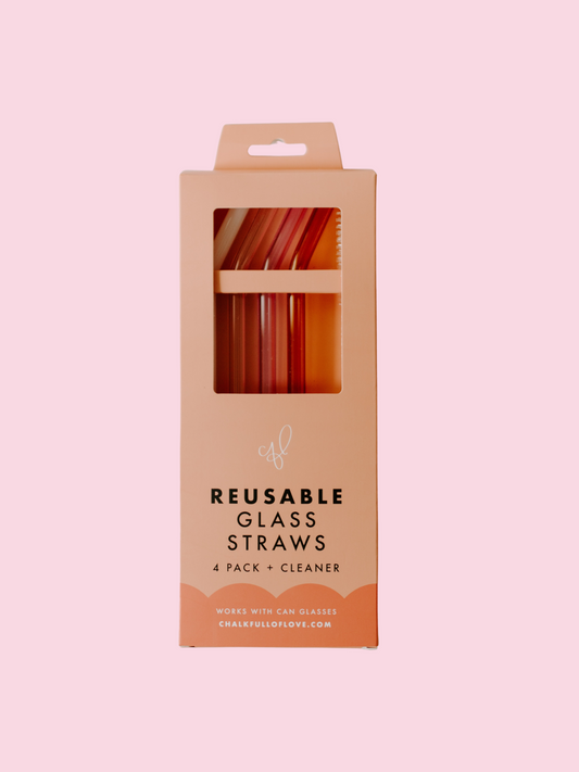 A pack of four multicolored glass straws in a cardboard packaging, with a label that reads 'Reusable Glass Straws'.