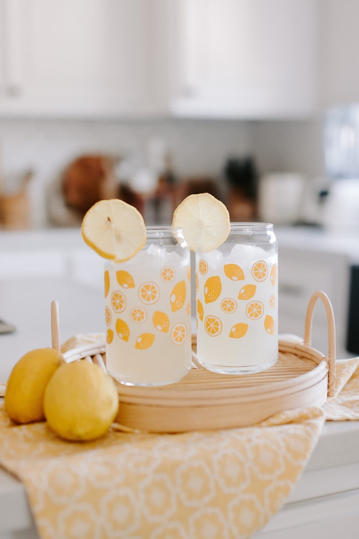 A clear can-shaped glass with lemon design wrapped around.