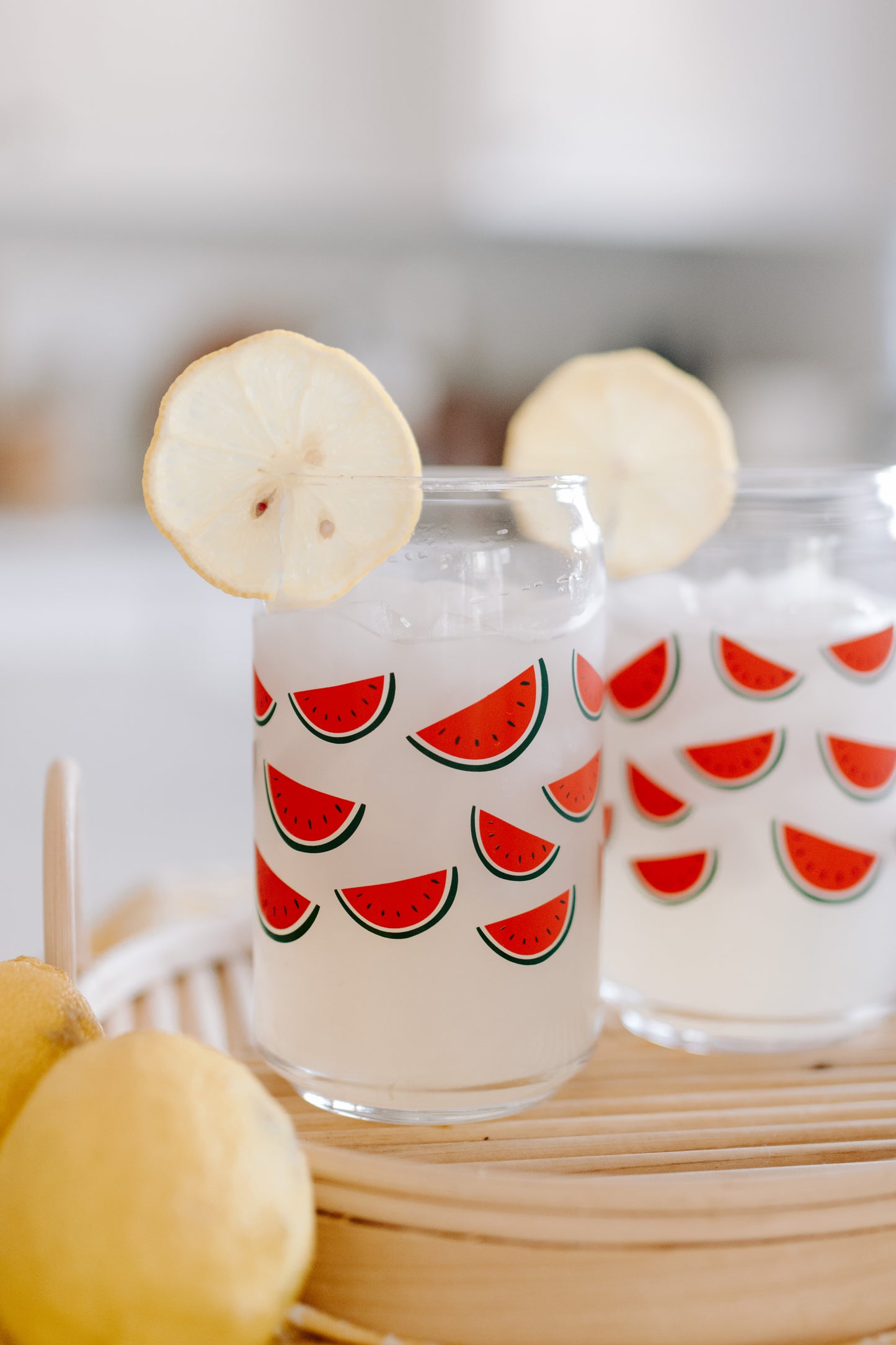 A clear can-shaped glass with watermelon design wrapped around.