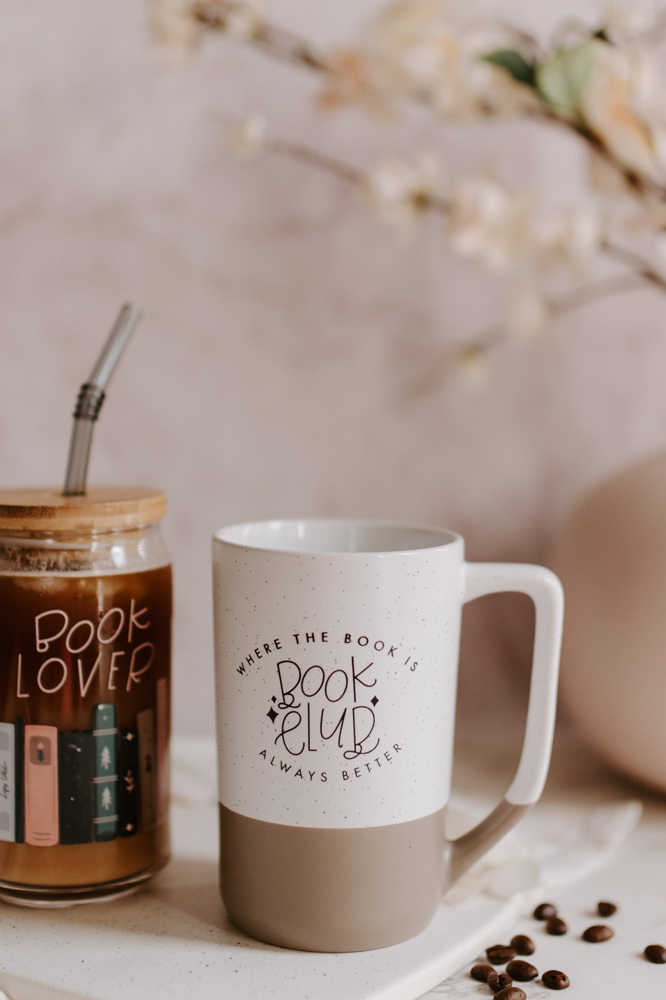 A two-tone ceramic mug with the upper part white with black speckles and the lower part taupe, featuring 'Book Club' text imprinted on the white part.