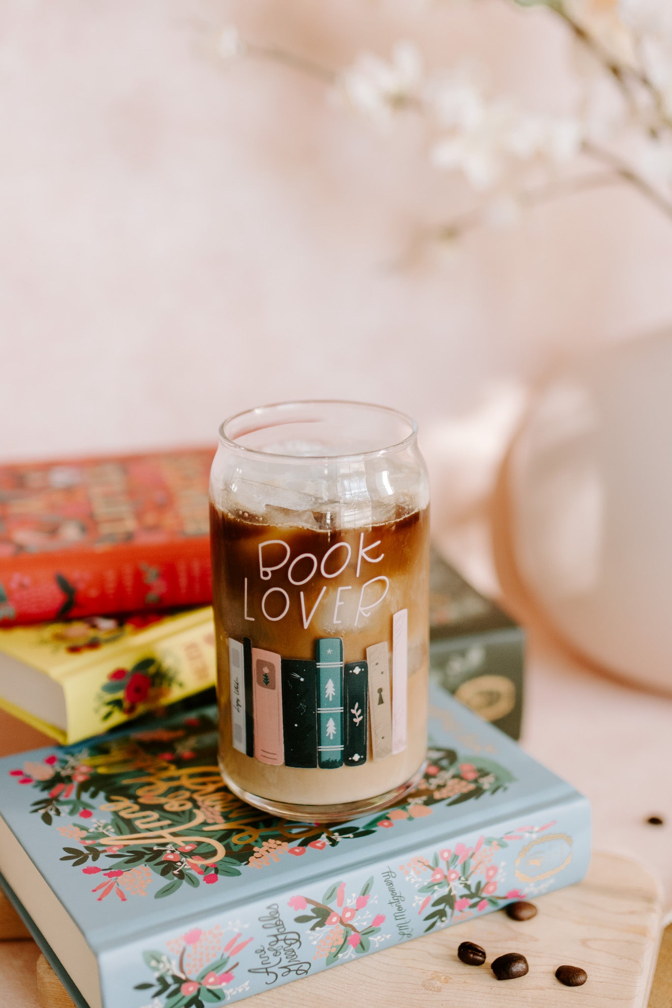 A clear glass can-shaped beverage holder with 'BOOK LOVER' text and a graphic of book spines on it.