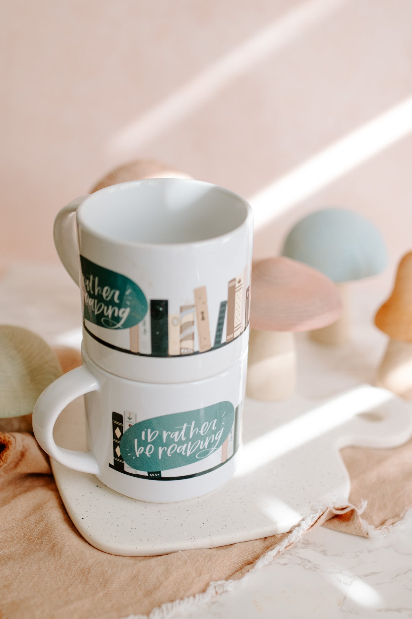 Glossy white mug with 'i'd rather be reading' and book graphic print wrapped around the mug