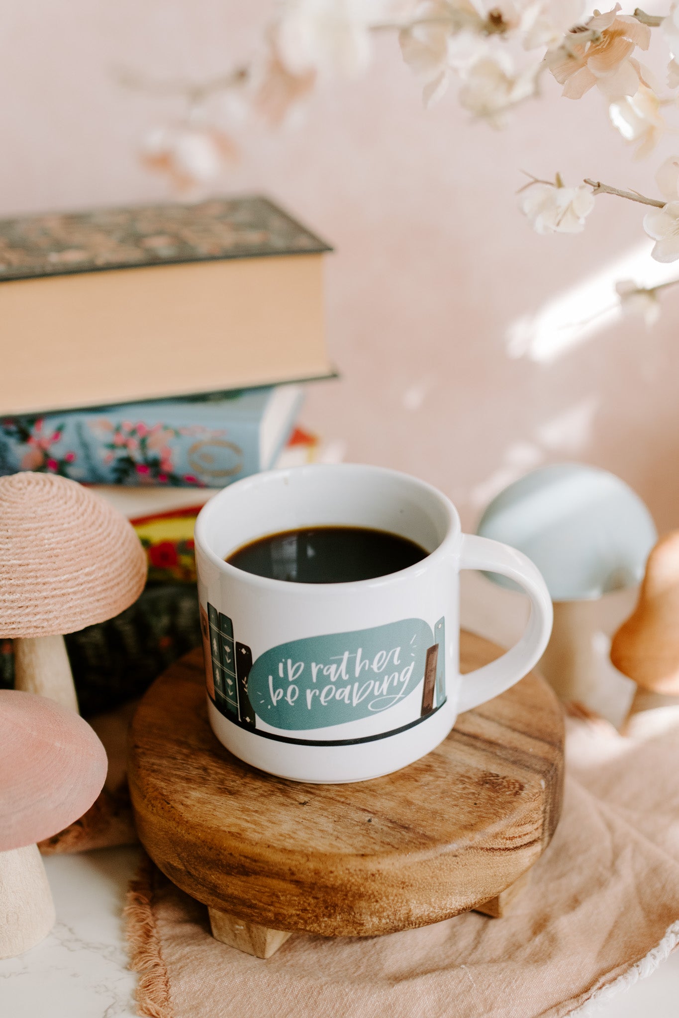 Glossy white mug with 'i'd rather be reading' and book graphic print wrapped around the mug