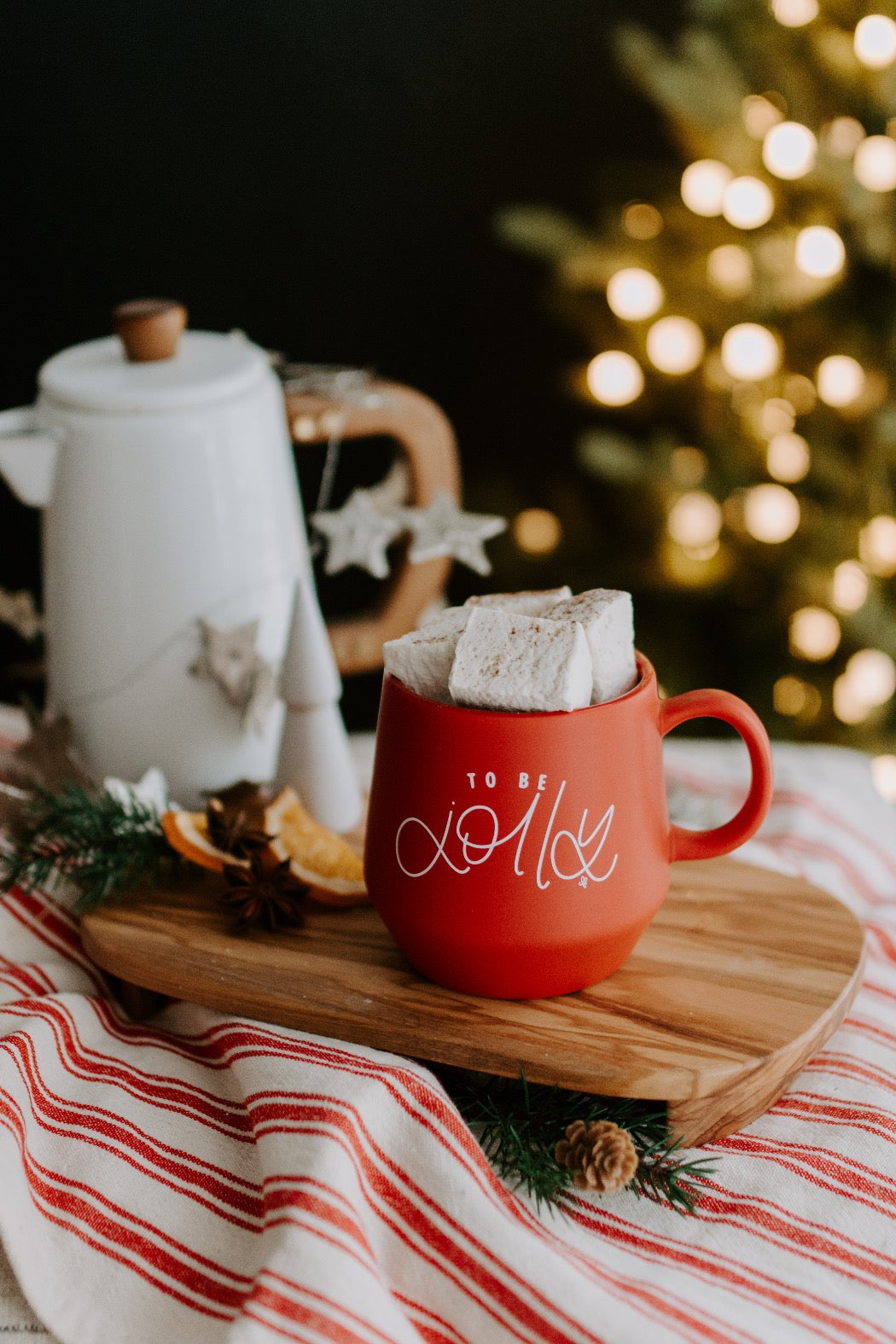 A red ceramic mug with the text 'to be jolly' written in hand lettered script on the side.