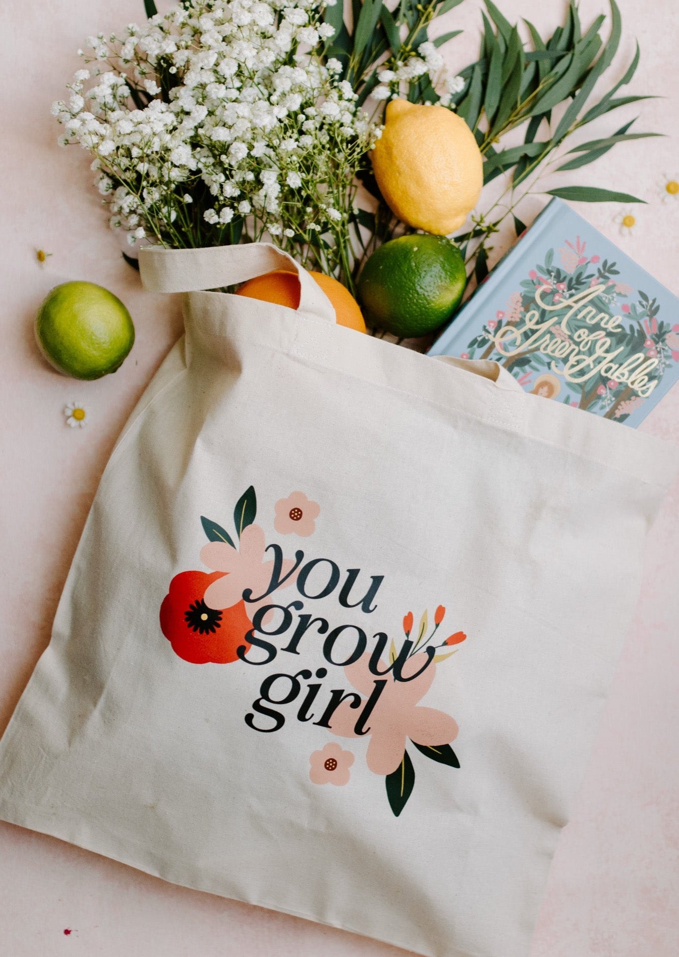 A white canvas tote bag with the text 'you grow girl' printed in black, surrounded by a floral design.
