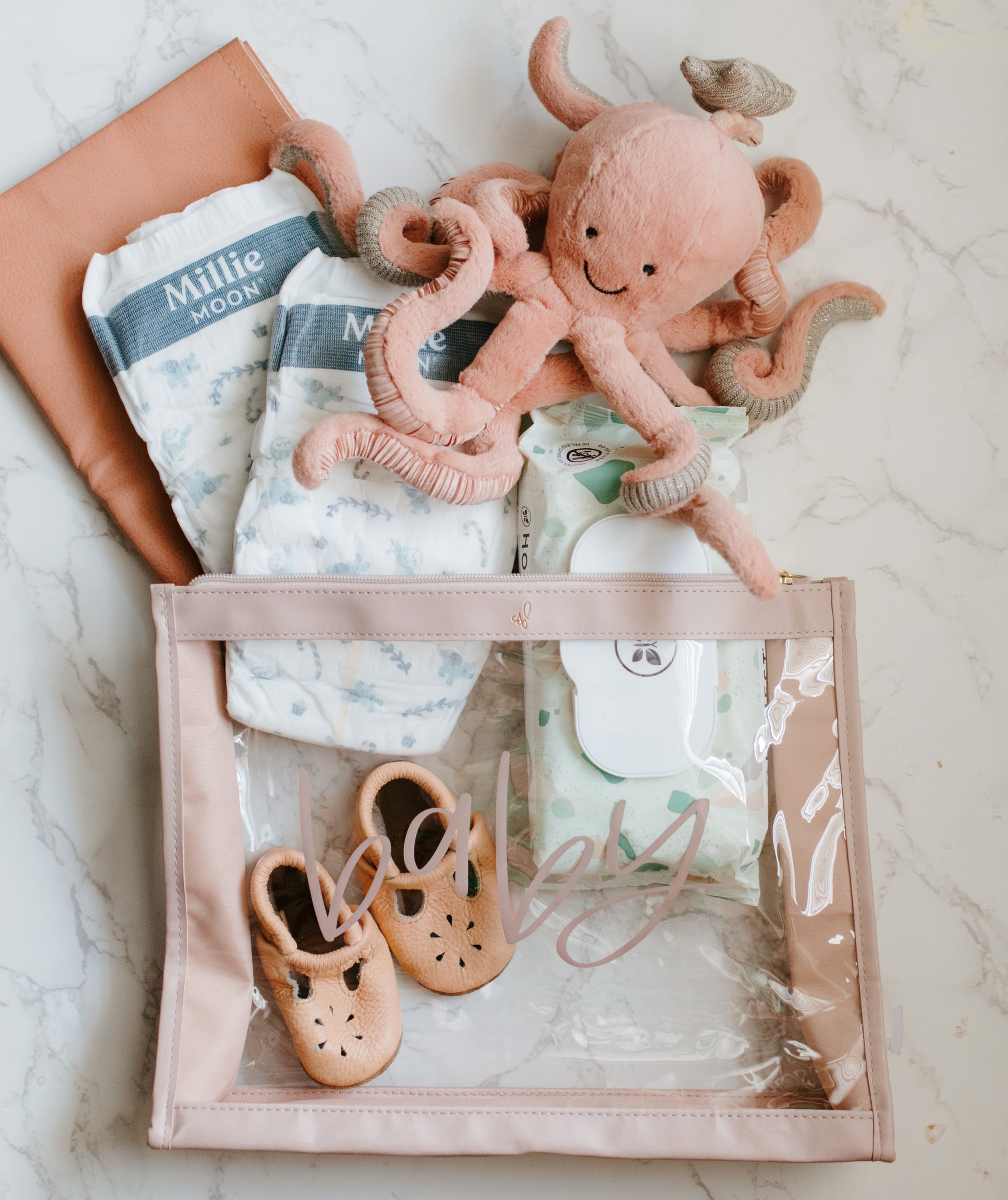 A clear vinyl organizer pouch with a 'baby' text in soft taupe color on the front, with a zipper closure and a taupe trim.