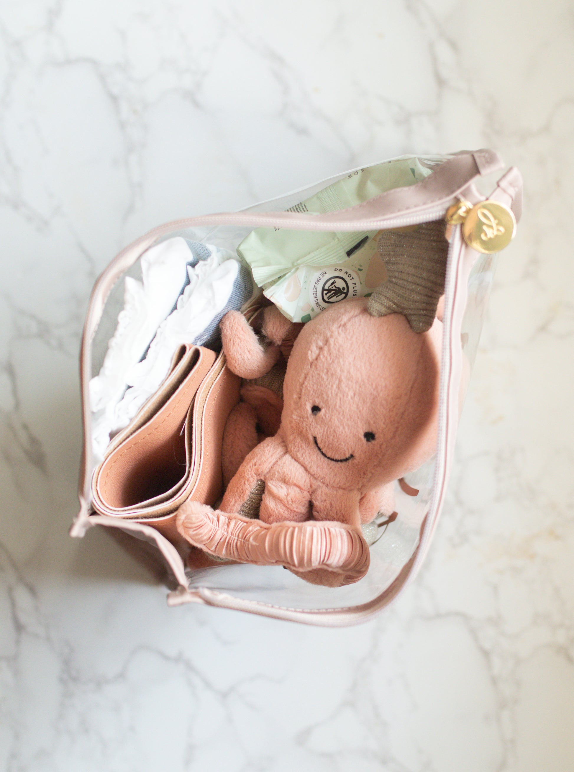 A clear vinyl organizer pouch with a 'baby' text in soft taupe color on the front, with a zipper closure and a taupe trim.
