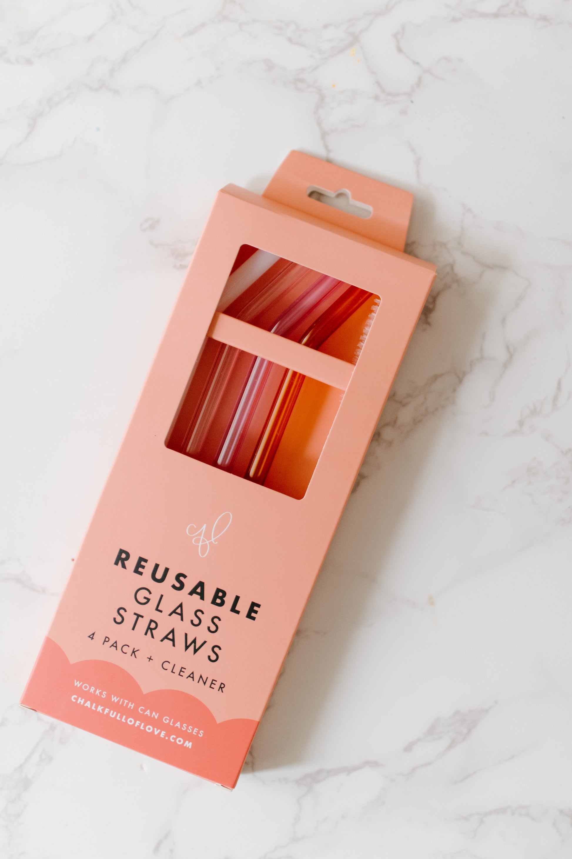 A set of four multicolored glass straws in Milky White, Lilac, Pink, and Amber colors packaged in peachy pink box