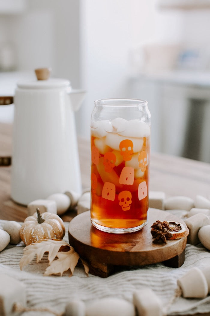 A 20 oz clear can-shaped glass with spooky cute pink ghost and orange skull design wrapped around.