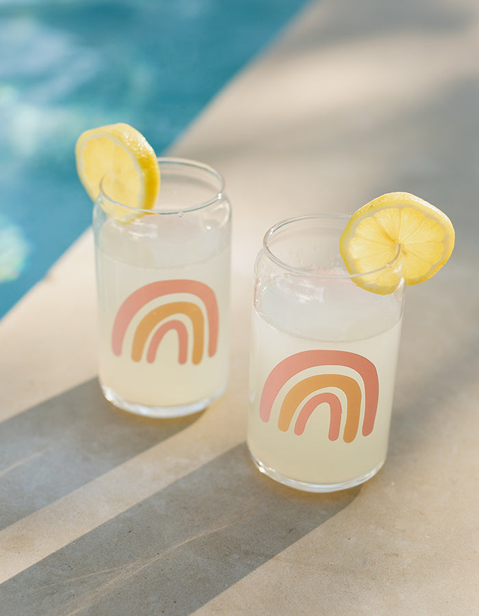 A clear glass with a rainbow design filled with ice and a beverage.