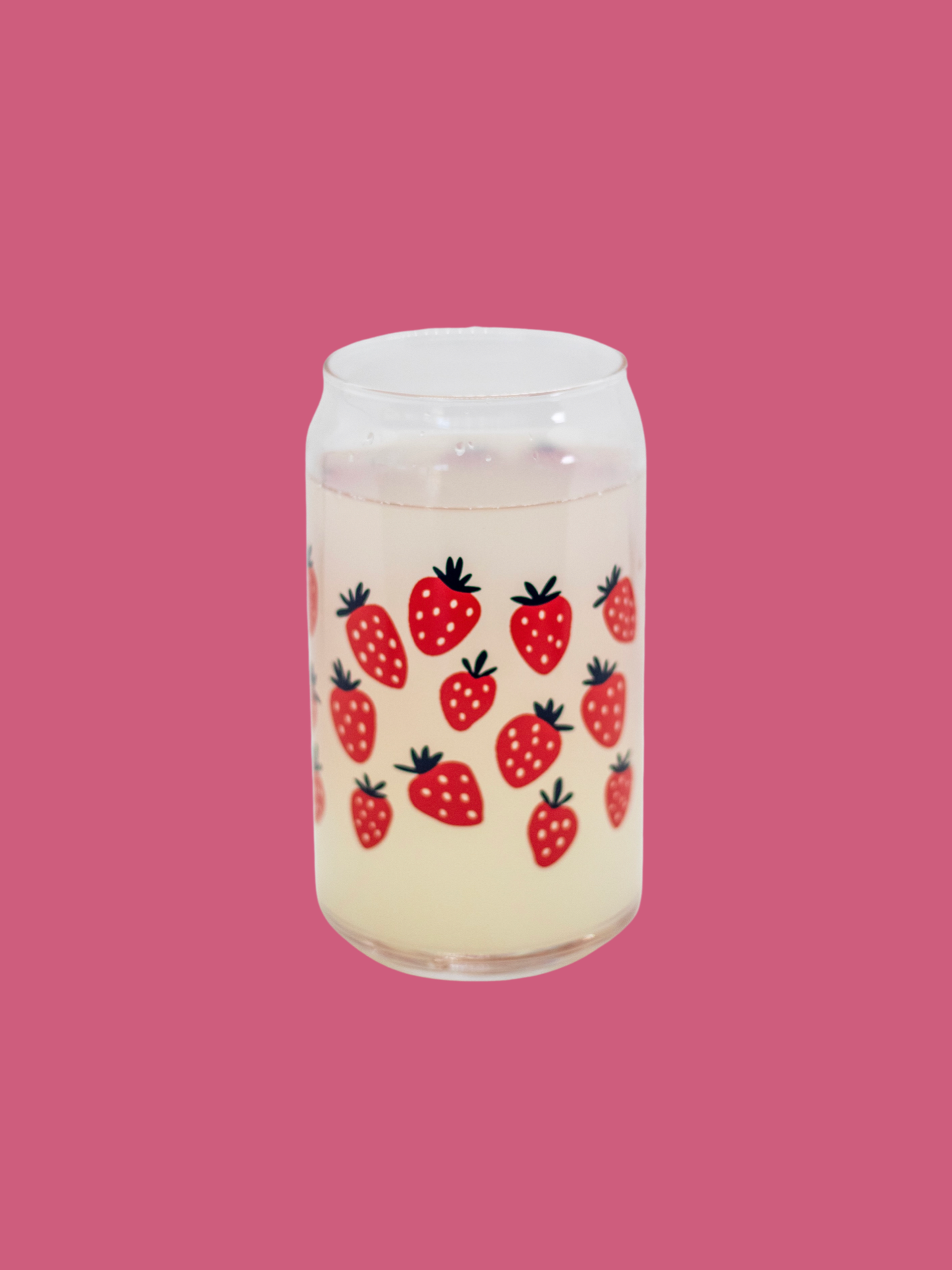 A clear can-shaped glass with strawberry design wrapped around.