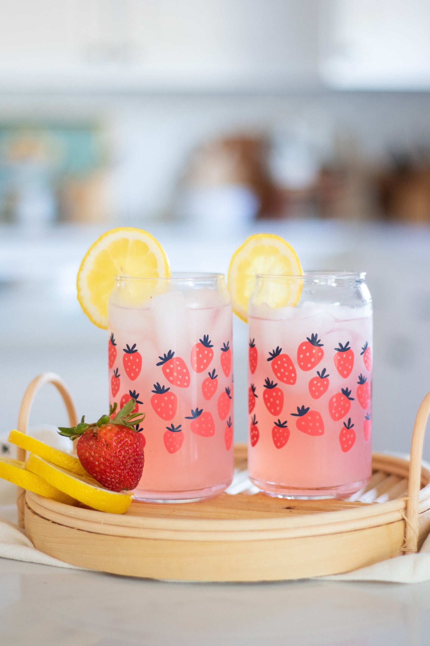 A clear can-shaped glass with strawberry design wrapped around.