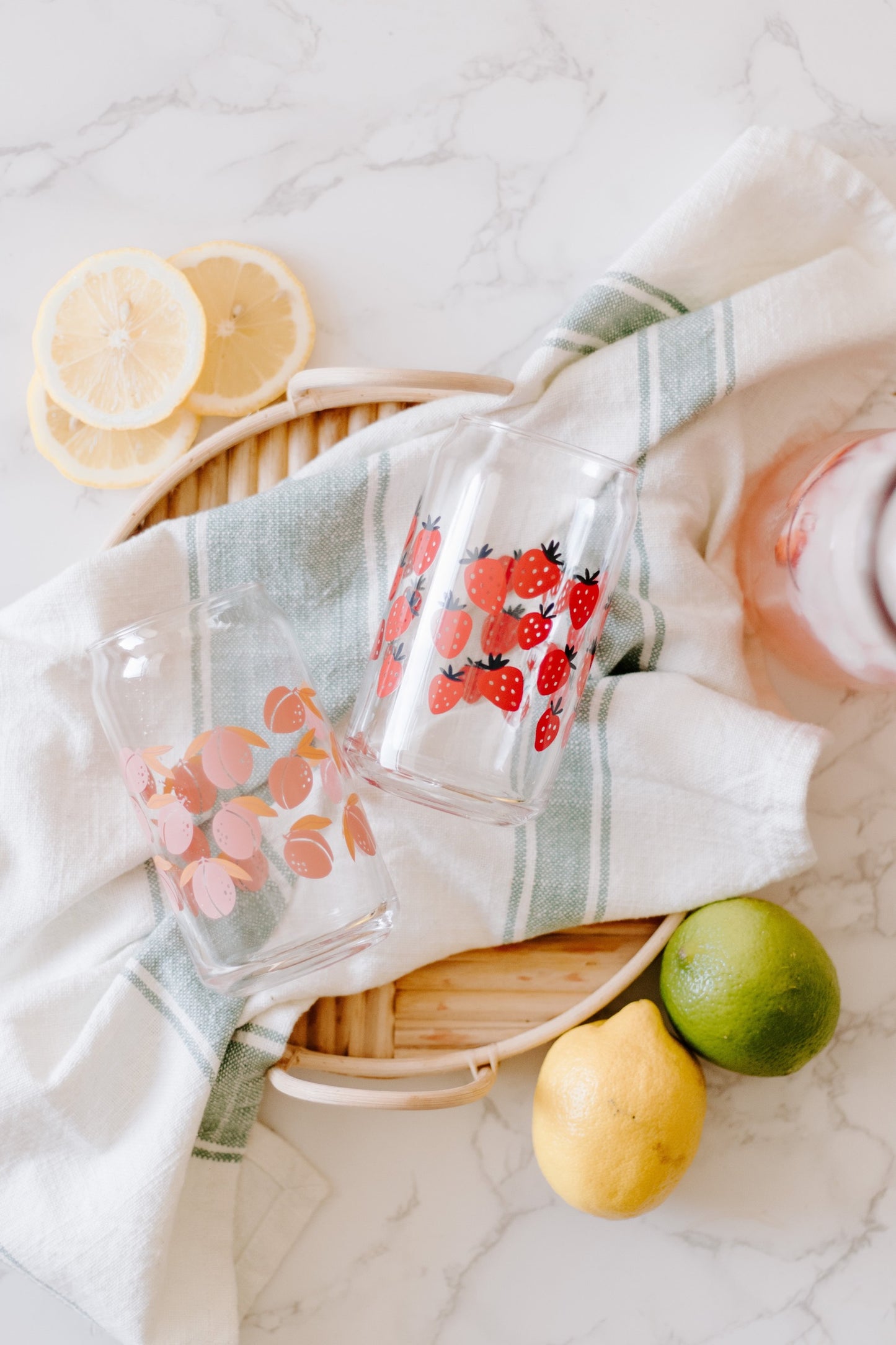 A clear can-shaped glass with strawberry design wrapped around.