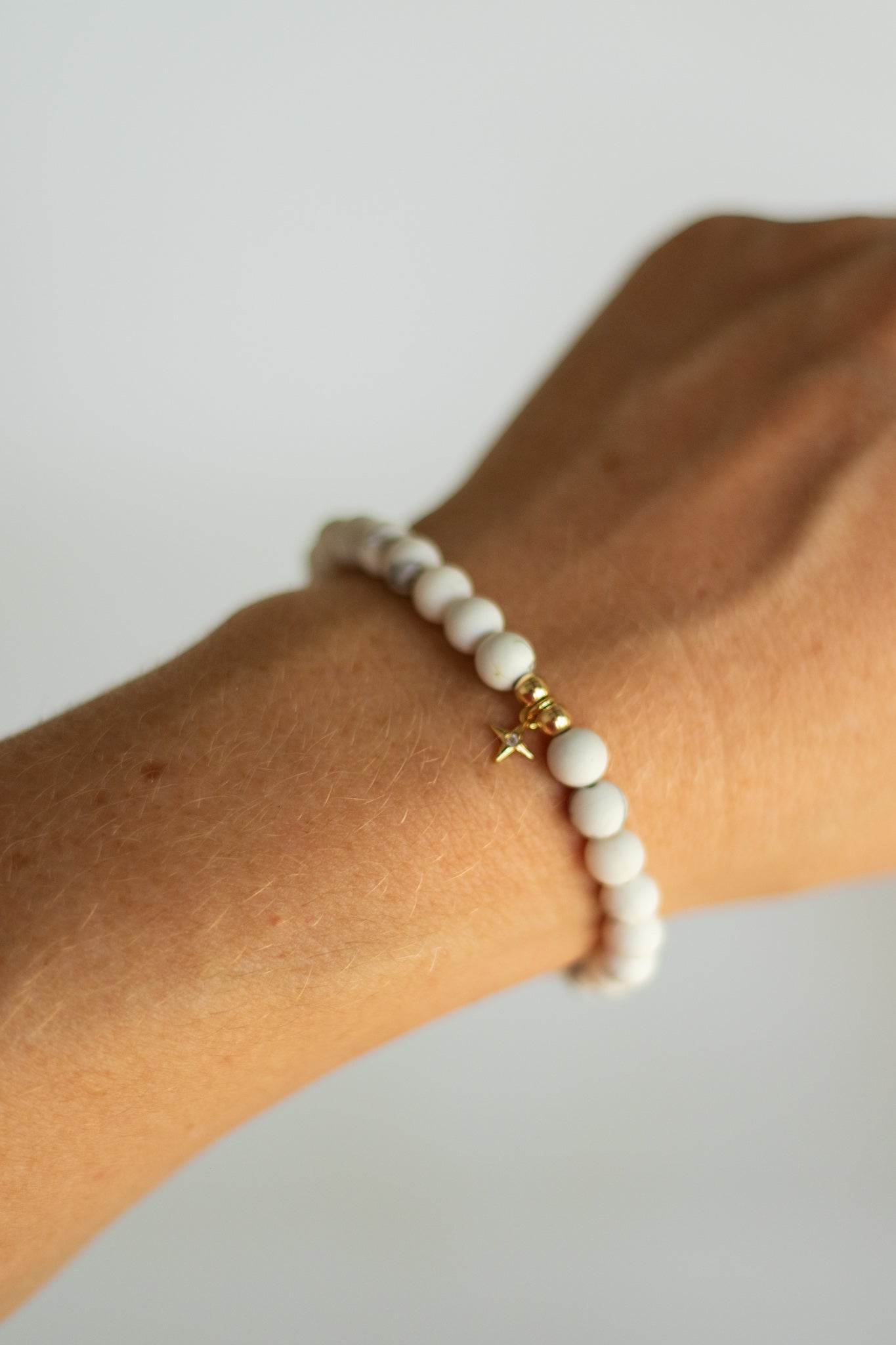 A white marble hematite bracelet with gold filled accents and a gold filled north star charm.