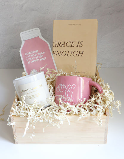 Gift basket with pink mug, white container, and pink product packaging on a light background