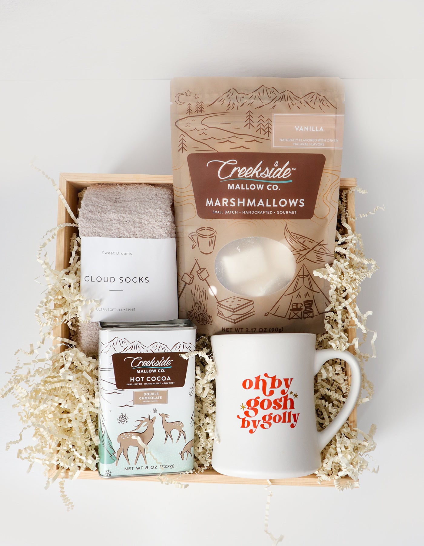 Gift set with marshmallows, hot cocoa mix, mug, and socks in a box.