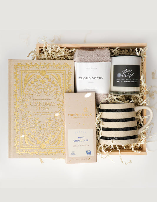 Gift set with a book, mug, chocolate, and candle in a wooden box.