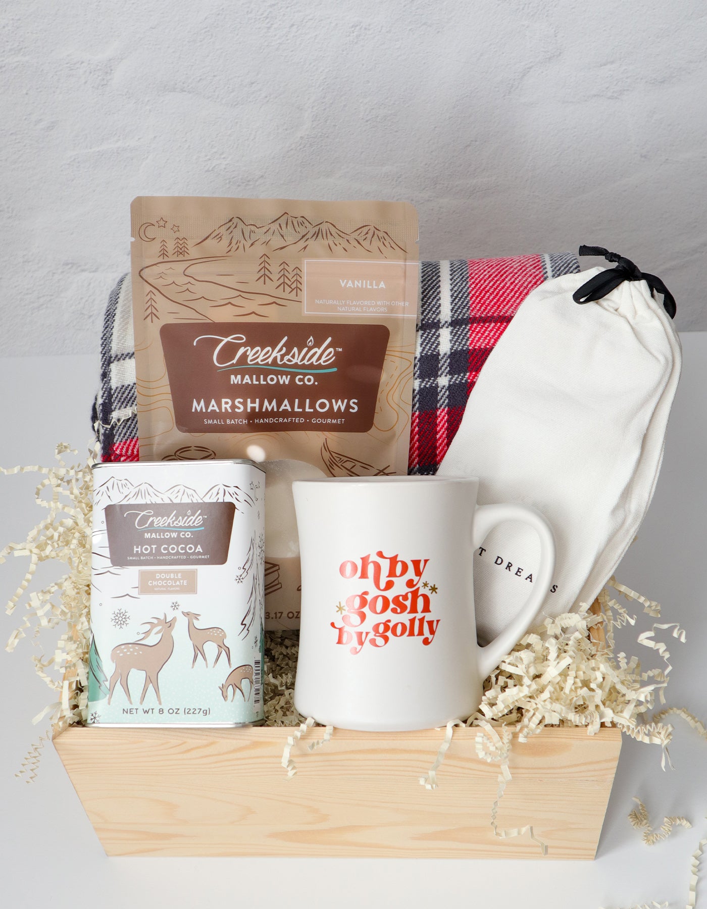 Gift basket with a mug, marshmallows, and hot cocoa mix on a gray background